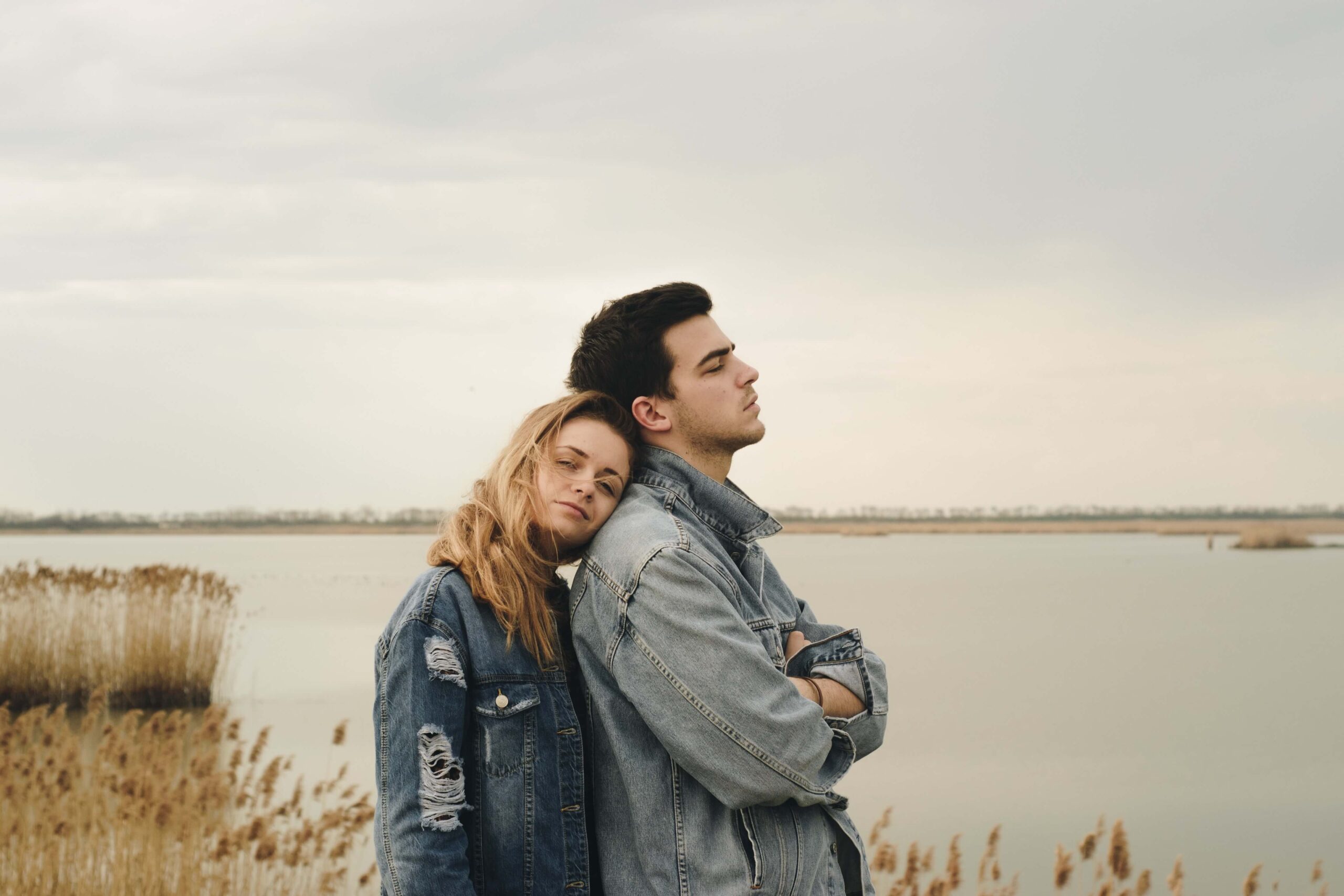 A somber-looking couple stands together at the bay