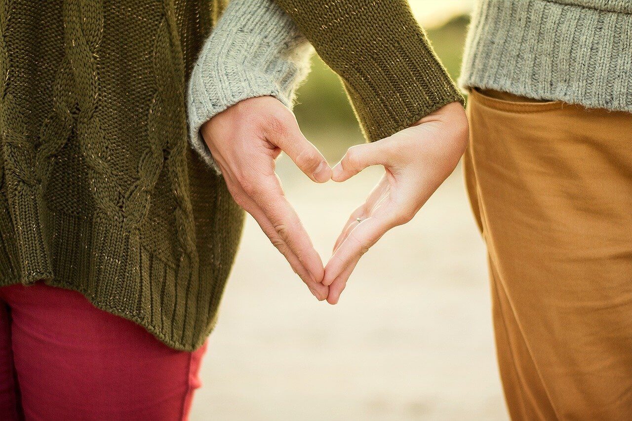 A couple with hands together forming a heart