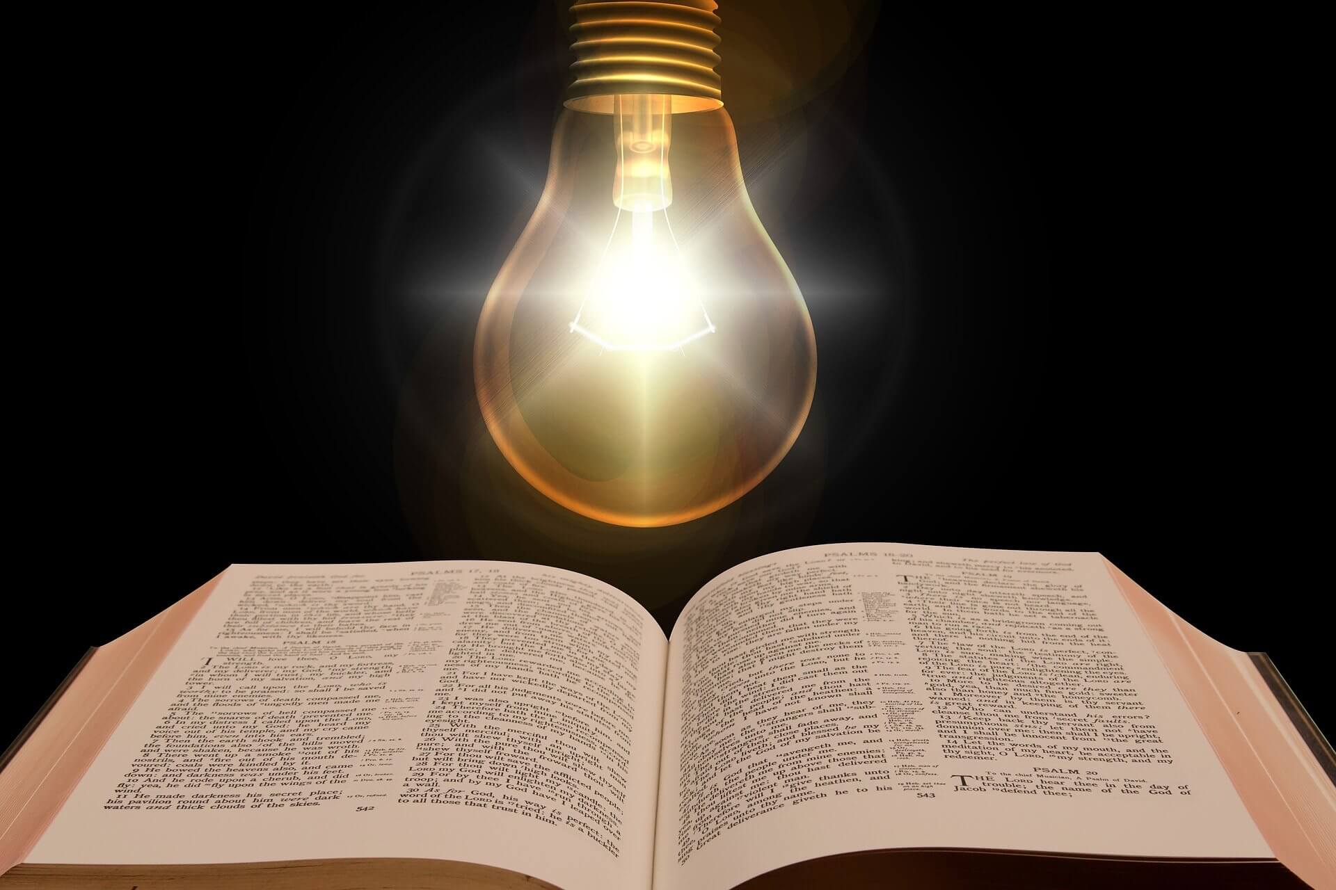 A shining lightbulb above an open Bible