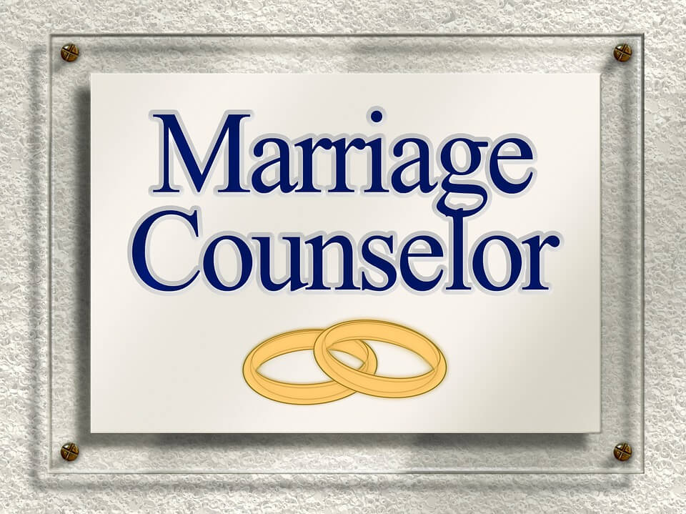 A sign with the words Marriage Counselor and two golden rings