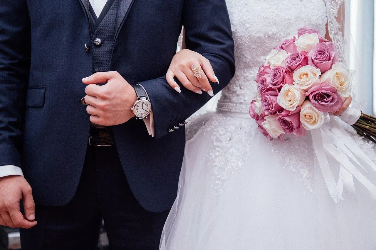 A close-up of a bride and groom linking arms