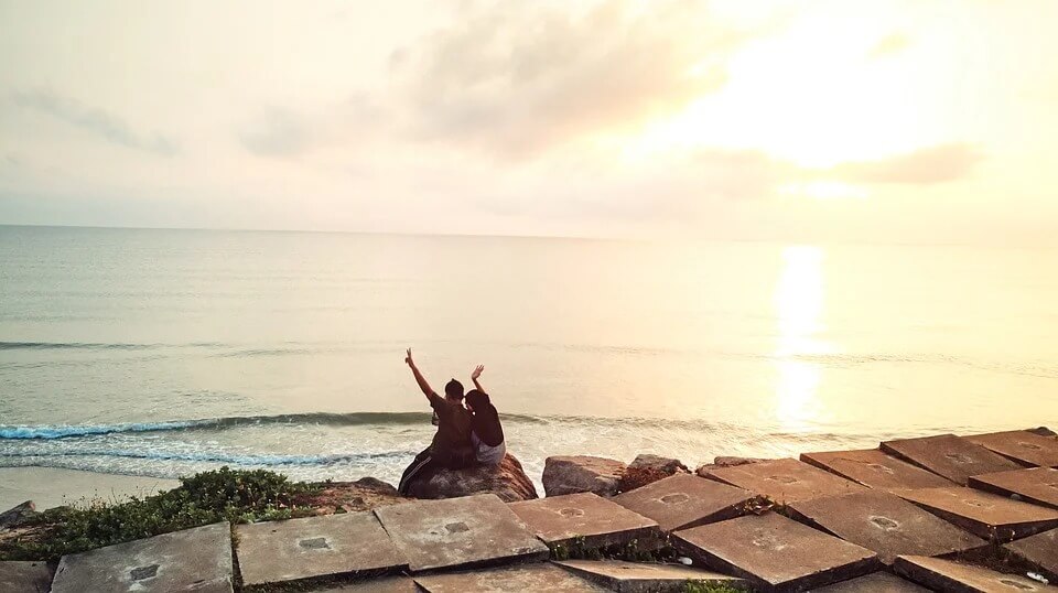 Couple sitting at beach sunrise