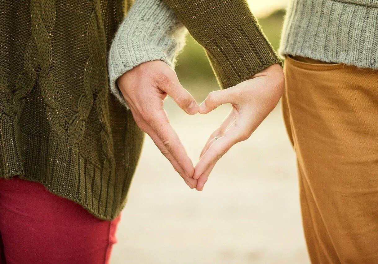 A couple with hands together forming a heart