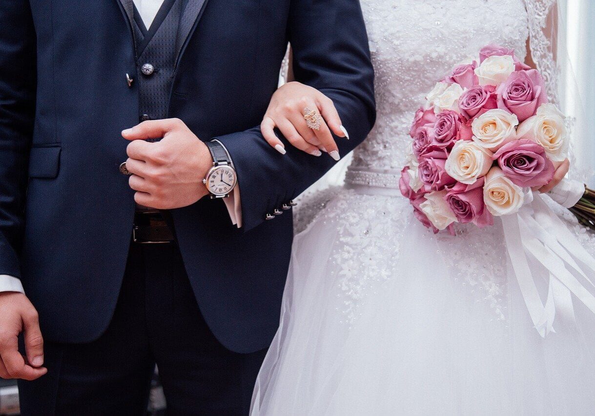A close-up of a bride and groom linking arms